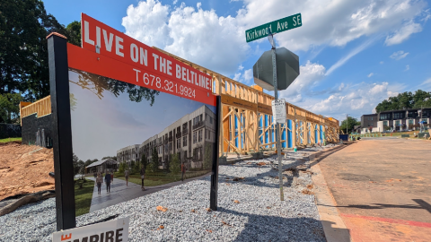 A photo showing a new row of condos being built under blue skies next to a large construction site in Atlanta.