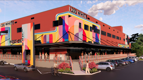 An image showing a huge brick warehouse in Atlanta under blue skies next a wide walking path and large streets. 