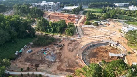 An image showing a large new greenspace under construction on the southside of Atlanta under gray skies with tiers and greenspace and a skyline in the distance, with many trees around. 