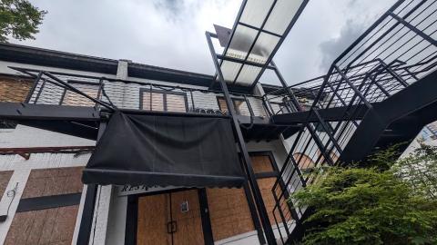 A photo of a site with many boarded-up buildings and overgrown yards and trash under gray skies in Buckhead Atlanta.