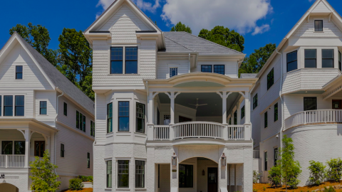 A site with a new community of large white victorian-style houses on a roundabout under blue skies outside Atlanta, Georgia. 