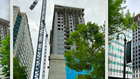 An image of a large tower under gray skies near many trees and wide street in Midtown Atlanta.