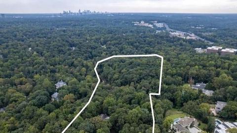 A photo of a large property of wooded land in a large city with cool old houses on it with tree views.