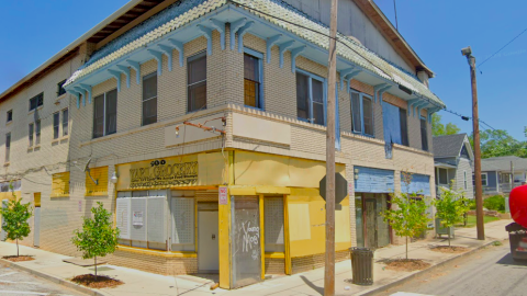 A large building on a corner under blue-gray skies in Atlanta with two stories and one corner painted yellow, with blue windows and vacant interiors. 