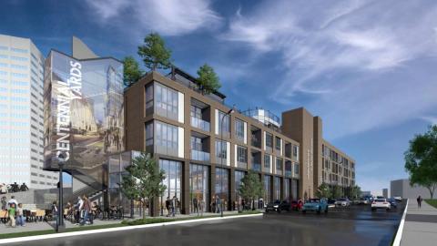 An image of a long four story building near a wide street with many tall buildings in the background in Atlanta. 