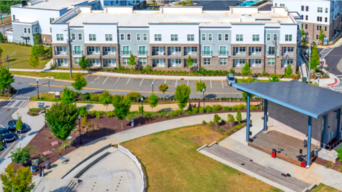 A new white and brick apartment complex in west metro Atlanta with many roads next door and modern interiors and a pool in the middle.