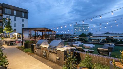 A new large apartment building with grill stations, a pool and other amenities over a large freeway in Atlanta under dark cloudy skies.