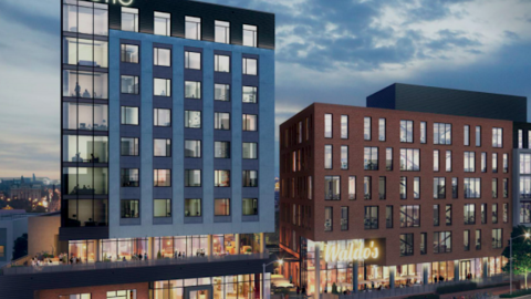 An image showing a large development site on a corner property under blue gray skies in Atlanta, with a Motto hotel at the corner.