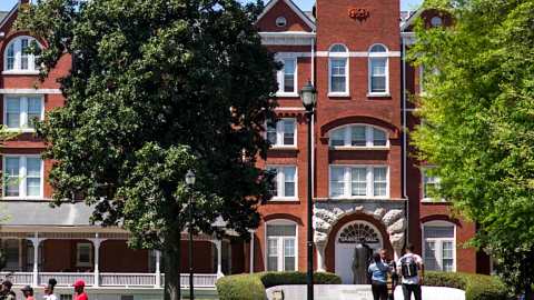 A large historic brick building in the middles of a leafy campus west of downtown Atlanta, shown in a photo. 