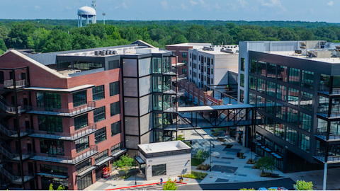 A photo of a large new complex in suburban Atlanta with new brick and glass buildings surrounded by wide streets and many green trees. 