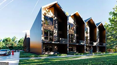 An image showing a site for 11 modern townhomes under blue skies near many trees and woods in Atlanta next to parking lots.