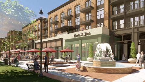 An image showing a mall location north of Atlanta where a large new community is planned with hundreds of homes and new parks with a fountain and many shops and restaurants, under blue skies.