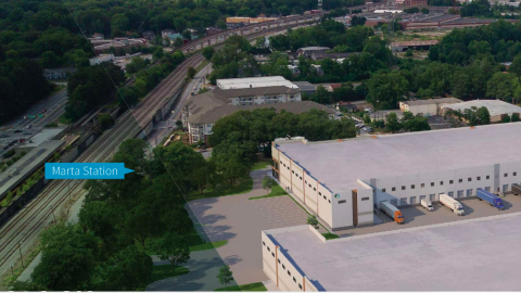 An image showing a large site with two long low warehouses built on it next to MARTA transit tracks and trees in Atlanta.