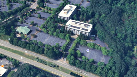 An overview of a site in suburban Atlanta where a large new development is planned on an office park near many trees and a wide highway.