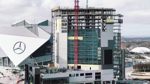 A photo of a large new modern-style tower next to a huge football arena in Atlanta.