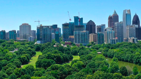 A photo of a large skyline with several new skyscrapers rising from the dirt around it near a huge green park in Atlanta.