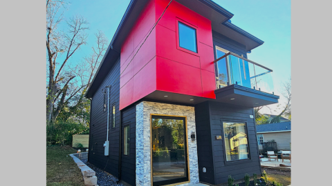 A photo of a red black and stone modern house with open contemporary interiors and floating stairs under blue skies south of Atlanta.