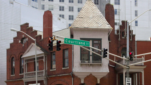 A photo of a three-story brick building from the 1800s with an ornate facade under many tall buildings around it in downtown Atlanta.