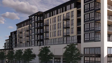 A large new black and white and gray apartment community under blue skies near wide roads in Atlanta.