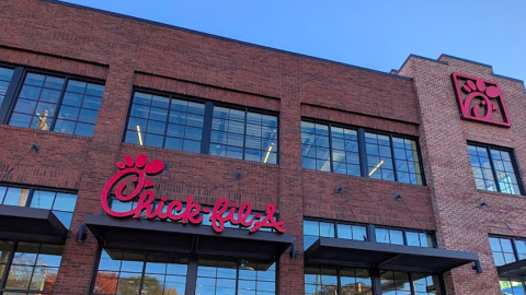 A photo of a new chick-fil-A restaurant with all brick sides under blue skies next to two wide streets in Atlanta.