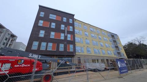 A new building of brick and plank shown under gray skies next to wide streets east of Atlanta.