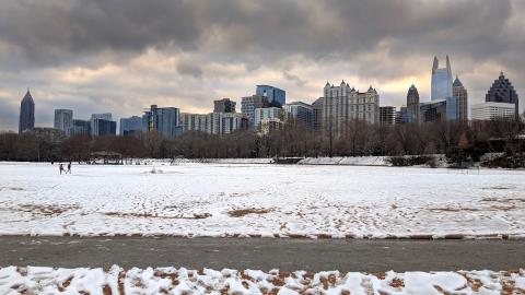 A photo of a large city blanketed in snow under cold gray skies with many buildings around.