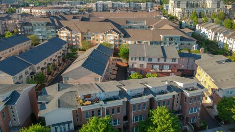 An aerial view over the tops of the many townhomes and apartments with skyscrapers in the distance.