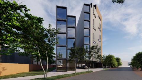 A modern gray and brown stack of apartments and office spaces under blue skies near a wide street on Atlanta's southside.