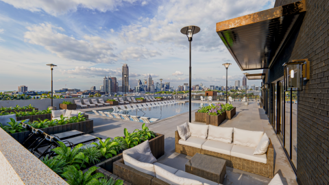 A rendering of a rooftop pool and hangout with a large city beyond under blue skies in Atlanta.