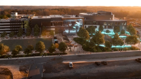 A large new TV and performance complex with white modern and concrete interiors surrounded by many homes, trees and smaller buildings south of Atlanta.