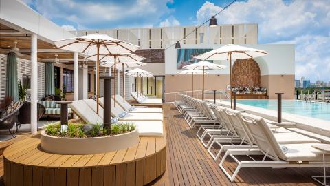 A photo of a large nice rooftop zone with restaurants and an infinity pool under blue skies in Atlanta.