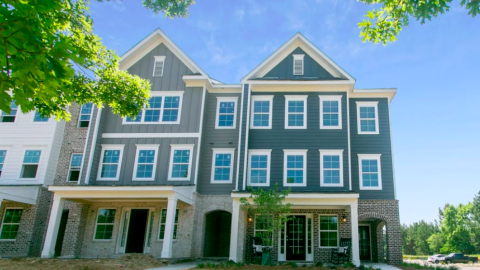 A photo of a large new townhome complex near green trees under blue skies in Atlanta.