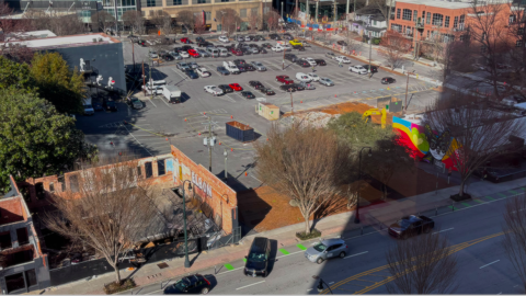 A large parking lot site shown with a few buildings near wide streets and many tall towers. 