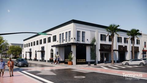 An image of a development site with a white existing former bank and empty parking lot near palms trees and two wide streets in Brunswick Georgia.