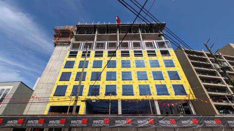 A photo of a large hotel project under construction beneath blue skies with yellow insulation near a wide street in downtown Atlanta Georgia.