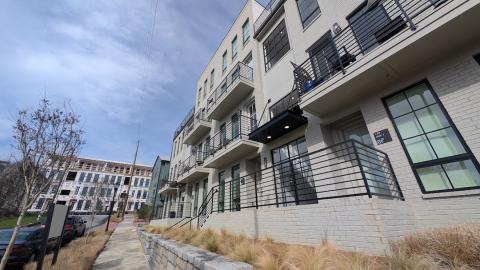 A photo of a large new housing development under blue skies in Atlanta along a paved blacktop street.