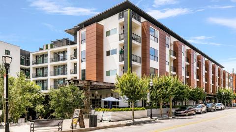 A photo of a large mid-rise building in the middle of an Atlanta neighborhood near wide busy streets.