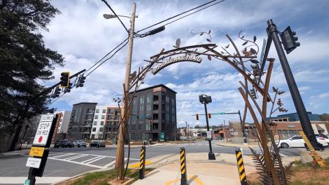 A photo of a concrete new bike and walking path under blue skies near woods and many industrial buildings in Atlanta, with yellow lines in the middle.