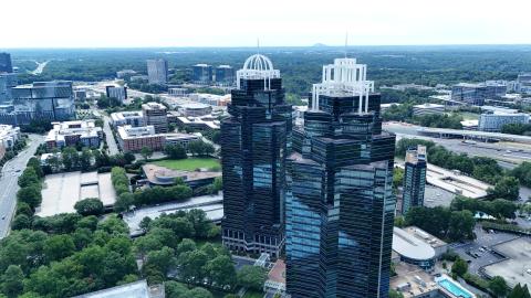 A photo of two dark-green glassy towers with white crowns in suburban Atlanta near many tall buildings and highways north of Atlanta, Georgia.