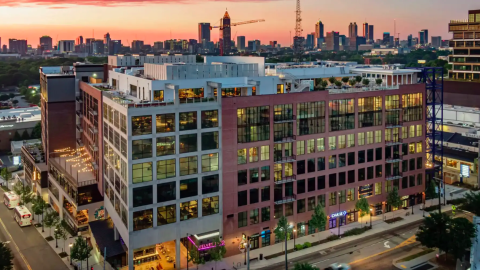 An overview of a large building in a big city with brick and glass and wide streets in front and back.