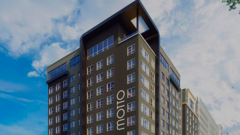 A rendering of a large dual-banded hotel building under blue skies along two wide and busy midtown Atlanta streets.