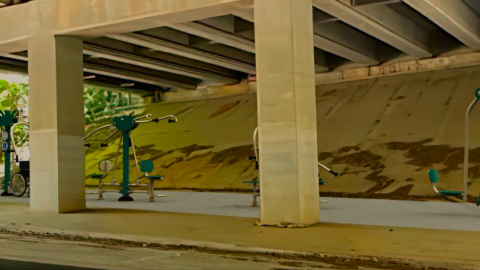 An image of a green outdoor gym under a freeway in Atlanta near a wide street.