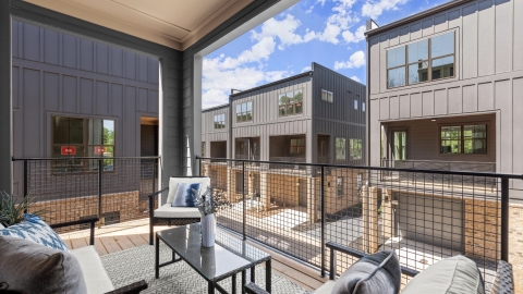 A photo of a black-clad and brick duplex building under blue skies on Atlanta's Westside with white modern interiors. 