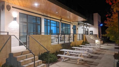 A photo of a large patio area along a sidewalk next to a modern white and black building under night skies in Atlanta.