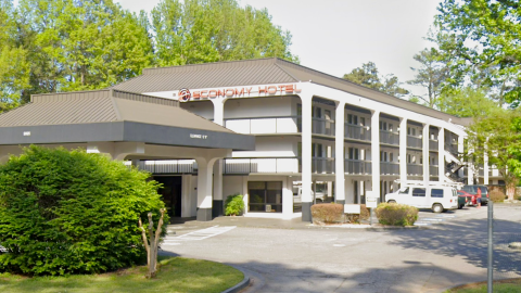 an image of a hotel in suburban Atlanta surrounded by many trees and streets and bushes that's been shut down recently for violations.