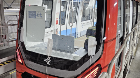 A new red train with an open interior on test tracks in Atlanta, with a worker inside.