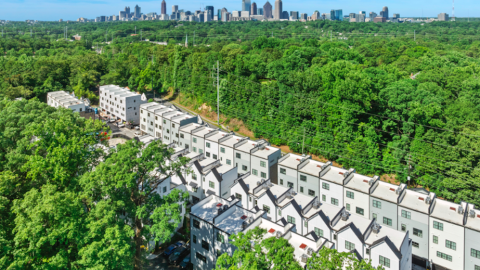 A photo showing rows of white tall new townhomes set among many trees near new streets in Atlanta.