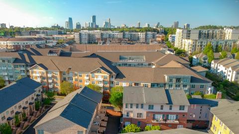 An aerial view over the tops of the many townhomes and apartments with skyscrapers in the distance.