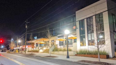A photo of a large new black and white building at night next to a wide street in Atlanta.