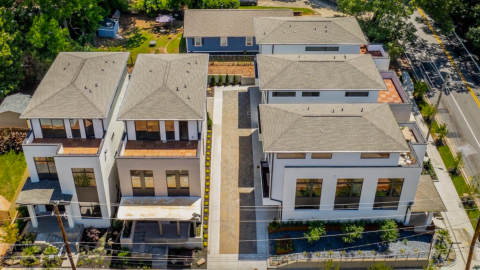 Drone photo of a large new home project with white brick and modern exteriors and a courtyard on wide streets.